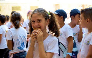 Una niña joven come comida en el patio de una escuela en Siria.