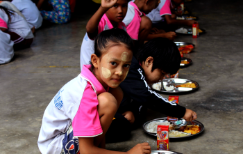 Los niños se sientan juntos para comer en una escuela en Tailandia.