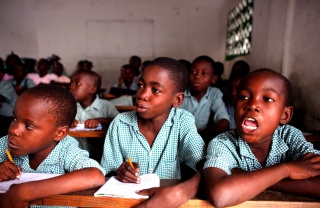 Tres niños se sientan juntos en clase en Haití.