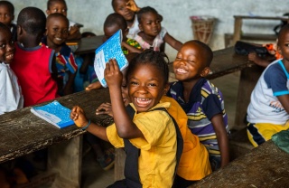 Una niña feliz sostiene su libro en clase.