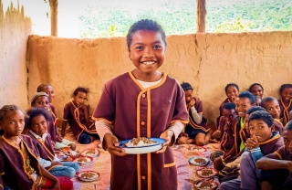 Un niño sostiene un plato de comida en Madagascar.