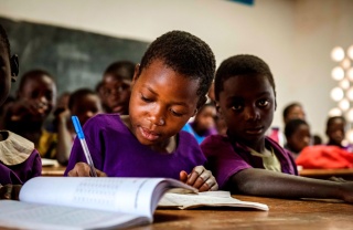 Un niño toma apuntes en clase en Malawi.