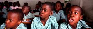 Tres niños se sientan juntos en clase en Haití.