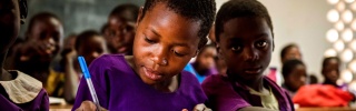 Un niño toma apuntes en clase en Malawi.