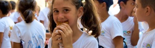 Una niña joven come comida en el patio de una escuela en Siria.