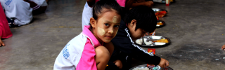 Los niños se sientan juntos para comer en una escuela en Tailandia.