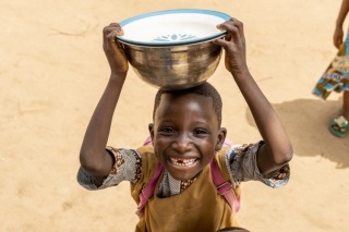 Un niño en Benin sostiene un tazón sobre su cabeza juguetonamente.