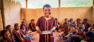 Un niño sostiene un plato de comida en Madagascar.