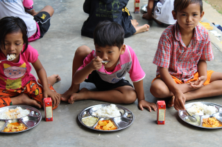 Los niños se sientan juntos para comer en una escuela en Tailandia.