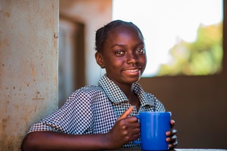 Una niña con una taza de comida en Zambia.