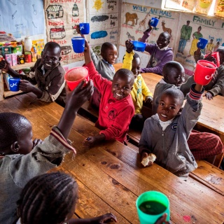 Una clase de niños levanta sus tazas.